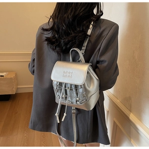 Detail of silver metallic mini backpack with pearl accents and embossed logo on model