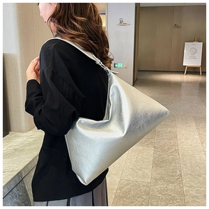 Silver metallic pleated faux leather hobo bag with wide shoulder strap on model