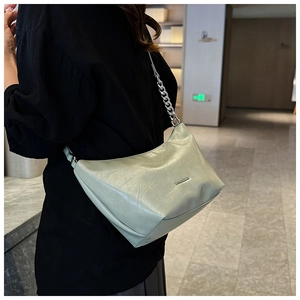 Detailed side view of light green leather shoulder bag with silver chain accessory
