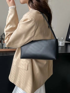 Minimalist black leather baguette bag for women styled with a beige blazer suit