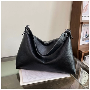 Detail of black dumpling tote bag with retro wrinkled texture and tassel side hardware
