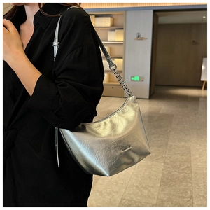 Detailed view of silver metallic pleated underarm bag with chain and logo on model