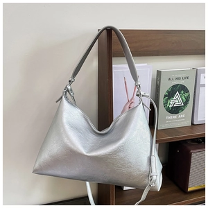 Detail view of silver tote bag hanging on a bookshelf with polished metallic texture