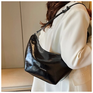 Detail of glossy black leather shoulder bag with adjustable strap and logo branding
