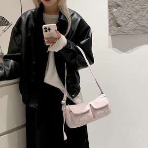 Detailed view of light pink nylon shoulder bag featuring dual front flap pockets