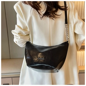 Detail of black leather hobo bag with silver chain strap and metal logo on white blazer