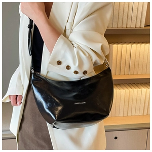 Detail of black semi-circle hobo bag featuring silver chain and metal logo branding