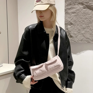 Pink nylon crossbody bag with dual utility pockets shown on a model in a leather jacket