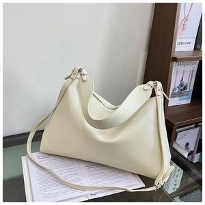 Close-up of cream Hobo bag with litchi texture on a glass table in a cozy room