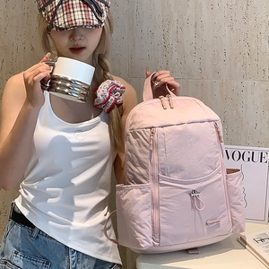 Detail of pink nylon backpack with multiple compartments shown in a lifestyle setting