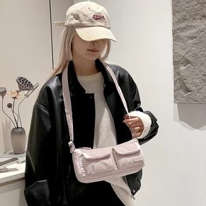 Detail of pink nylon crossbody bag featuring double front flap pockets and adjustable strap