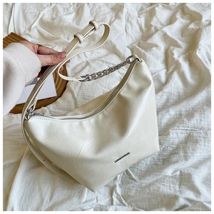 Detailed macro of cream faux leather hobo bag with silver chain and adjustable strap