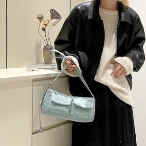 Detail of mint green nylon messenger bag with front flap pockets on a shoulder strap