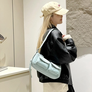 Detail of light blue nylon biker bag featuring multiple utility pockets and crinkled texture