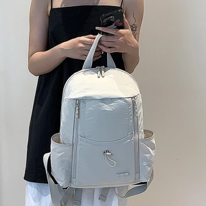 Detail showing hand-held casual nylon backpack with pleated texture and utility pockets