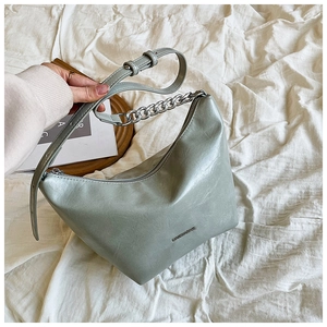 Detail of sage green hobo bag with matte leather texture and silver chain strap