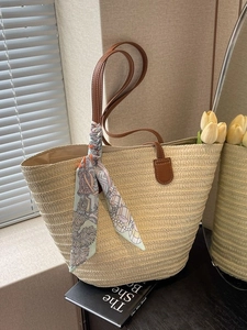 Straw beach tote bag with leather handles and decorative silk scarf for summer