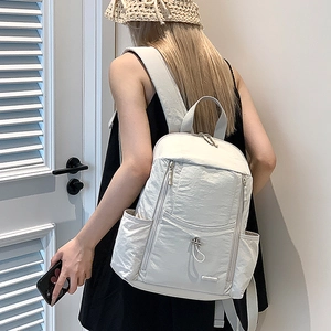 Rear view of a cream nylon backpack on a model showing large capacity and daily comfort