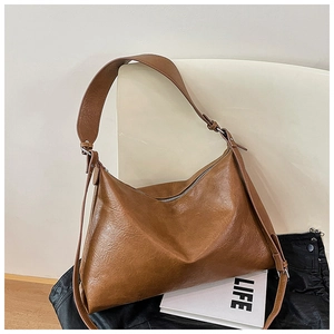 Detail of a brown leather-textured tote bag showing vintage pleats and silver hardware