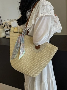 Large straw tote bag with brown leather straps and floral silk scarf for summer beach