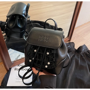 Close-up of black leather mini backpack featuring pearl drawstring and embossed logo detail