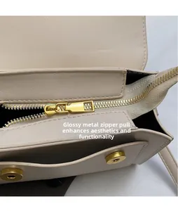 Detailed macro view of the gold-tone metal zipper and beige leather interior of the handbag