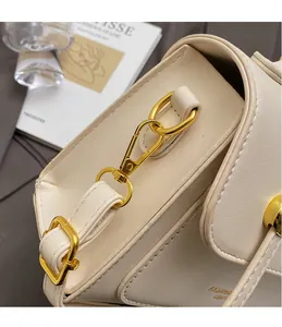 Close-up of golden hardware hooks and fashion leather embossing on cream handbag