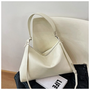 Macro shot of off-white textured leather hobo bag with wide strap on modern chair