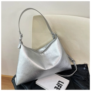 Detailed shot of silver metallic tote bag with pleated texture on a minimalist white chair