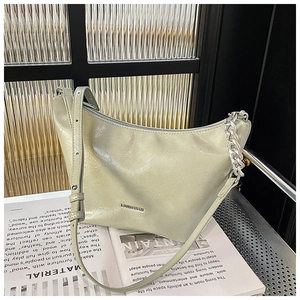 Detail view of the silver decorative chain and leather strap on a light green handbag
