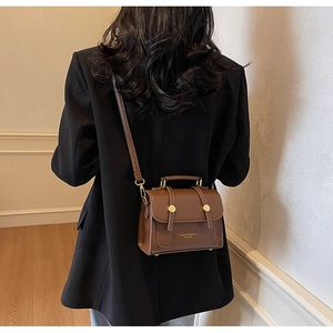 Close-up of brown leather crossbody bag with gold hardware and removable shoulder strap