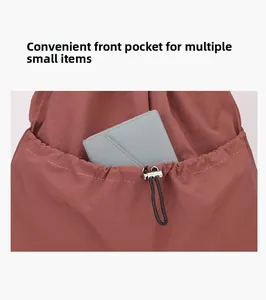 Detail of drawstring front pocket on brick red nylon backpack with grey wallet inside