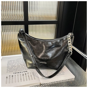 Close-up of black glossy hobo bag with silver chain detail and sleek metal brand logo
