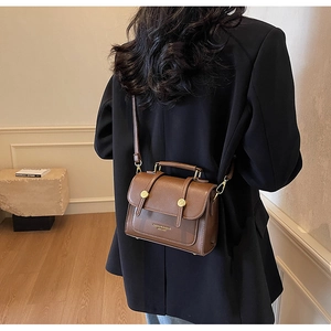 Detail view of the brown leather texture and gold hardware on this chic crossbody bag