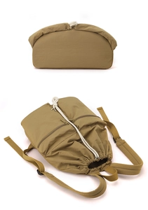 Detailed close-up of khaki nylon drawstring backpack showing base and front zipper pockets