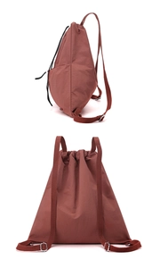 Close-up of the brick red drawstring backpack showing adjustable buckles and nylon texture