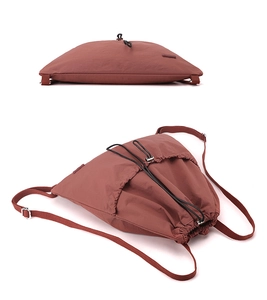 Top view of brick red drawstring backpack showing durable nylon fabric and black cords
