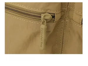 Close-up of the smooth zipper and high-quality nylon stitching on the khaki backpack