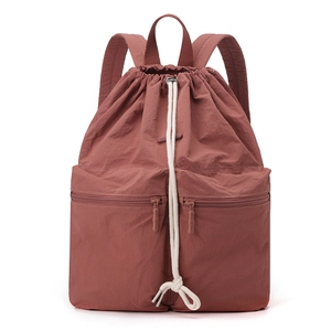 Detail of water-resistant nylon drawstring backpack in rust red with white cotton cords