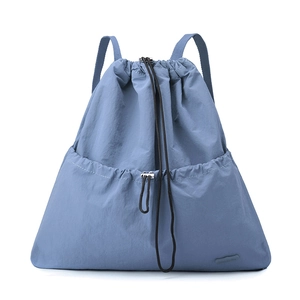Detail of blue nylon drawstring backpack showing front pocket and metal fastener