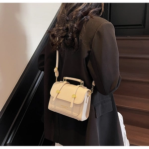 Detailed view of cream leather crossbody bag with gold hardware worn by a model