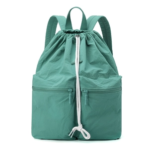 Macro detail of mint green nylon drawstring backpack with zipper pockets and logo