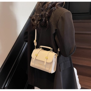 Detail of cream leather handbag with gold round buckles and metallic handle on model
