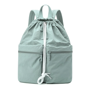 Macro detail of mint green nylon drawstring backpack with front zippered pockets
