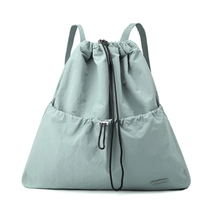 Detail of mint green nylon drawstring backpack featuring adjustable straps and front pocket