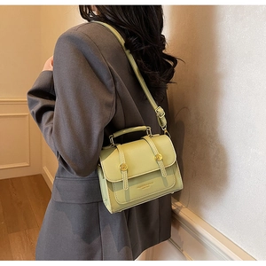 Detail of light green leather crossbody bag with gold round lock and fashion logo text