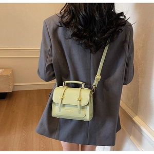 Detail of light green leather crossbody bag with gold hardware on a gray blazer suit