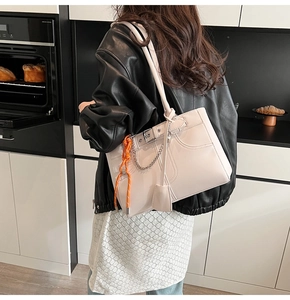 Dettaglio borsa tote color crema in PU con corda arancione e catena d'argento decorativa
