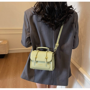 Rear view of mint green leather crossbody bag featuring gold hardware and metal feet