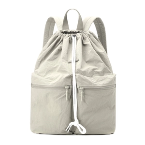 Detail of light grey nylon backpack with drawstring closure and dual front zipper pockets